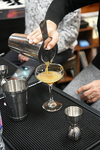 A customer pouring a martini into a glass from a Boston shaker using Durham Distillery's London Calling Dry Gin