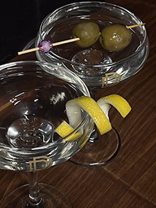 A picture of two maritini's, one wth a lemon garnish and one with a olive garnish.