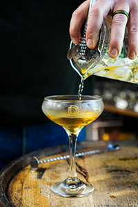 Pouring a Manhattan cocktail into a Durham Distillery Coupe Glass