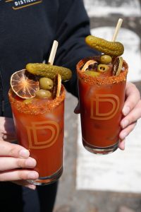 Two Canadian Caesar cocktails in tall highball glasses with garnishes